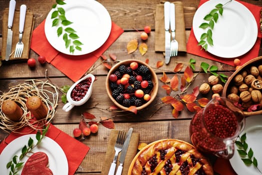 Fresh rennets, walnuts, pastry, jam, fruit drink, berries and tableware on served table