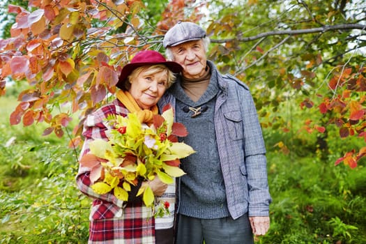 Happy senior couple under branch looking at camera