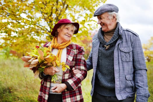Romantic seniors taking walk in park in autumn
