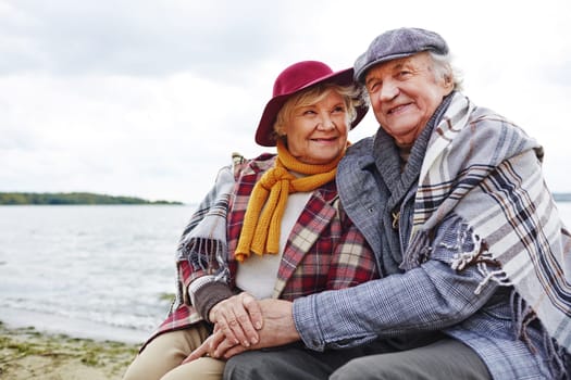 Retired seniors having rest by seaside in autumn