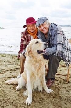 Retired couple with labrador spending time by seaside