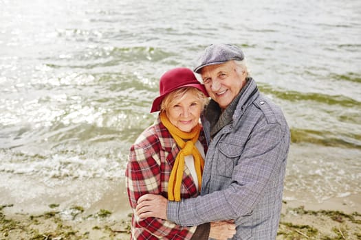 Happy aged couple by seaside looking at camera