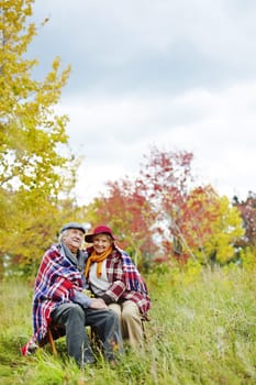 Old man and woman in warm clothes enjoying rest in park