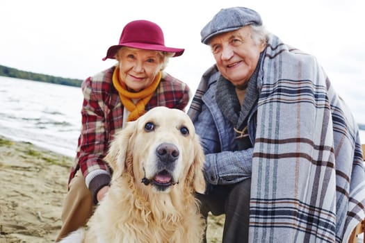 Retired couple and their pet relaxing by seaside on weekend