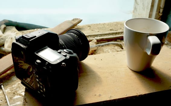 camera and cup on wooden tray on site