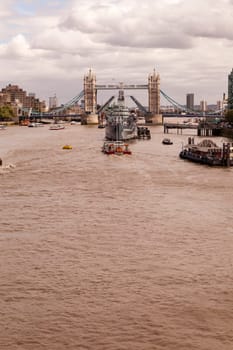 London, United Kingdom - August 04, 2015: Decommissioned battleship HMS Belfast in River Thames moored between London Bridge City Pier and one of Britain’s most famous landmarks, The Tower Bridge.
