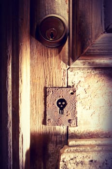 Old wood door with spooky skull keyhole vintage background ideal for Halloween poster.