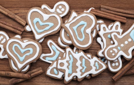 Decorated gingerbread cookies with cinnamon sticks on a wooden background