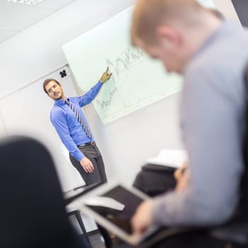 Business man making a presentation at office. Business executive delivering a presentation to his colleagues during meeting or in-house business training, explaining business plans to his employees.