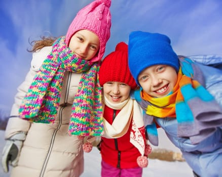 Joyful kids in winterwear looking at camera in natural environment