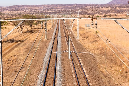 Railway train tracks line travel through dry season rural landscape