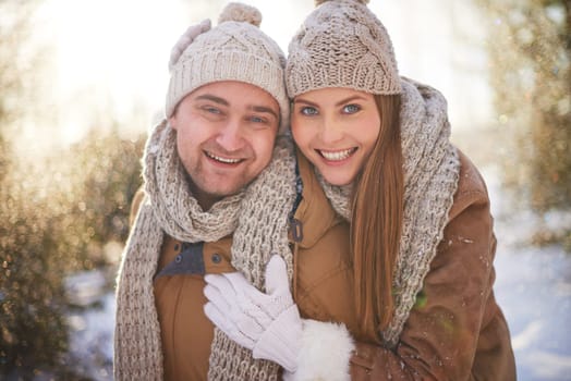 Cheerful dates in winterwear looking at camera with smiles