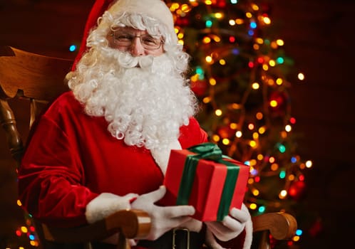 Santa Claus sitting on background of sparkling firtree