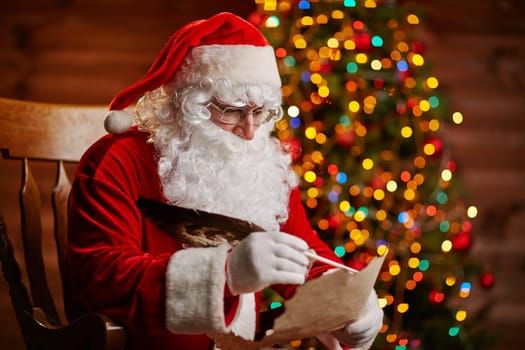 Santa Claus answering Christmas letter by sparkling firtree