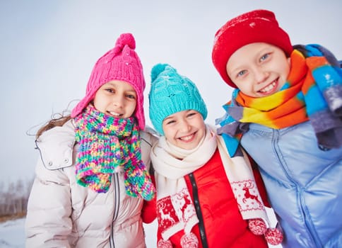 Joyful friends in winterwear looking at camera outdoors