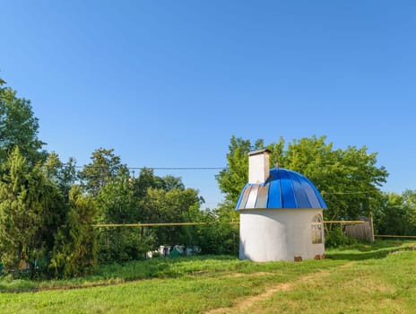 Small round house with blue domed roof on green lawn on sunny summer day.