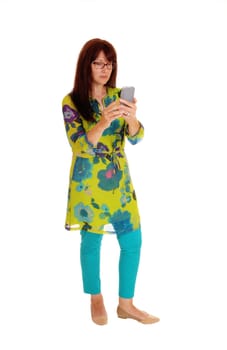 A business woman in a colorful dress dialing on her cell phone, standing.isolated for white background..