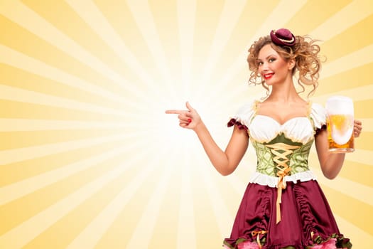 Beautiful smiling sexy Oktoberfest waitress wearing a traditional Bavarian dress dirndl holding beer mug, and pointing aside on colorful abstract cartoon style background.