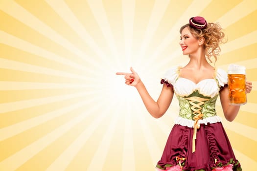 Beautiful smiling sexy Oktoberfest waitress wearing a traditional Bavarian dress dirndl holding beer mug, and pointing aside on colorful abstract cartoon style background.