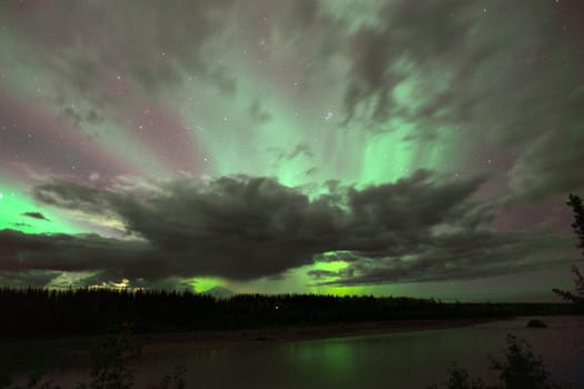 The Northern Lights emerge through the clouds in remote Alaska