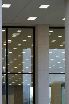Abstract square ceiling lights are reflected in the glass panes of a panoramic window or shop window.