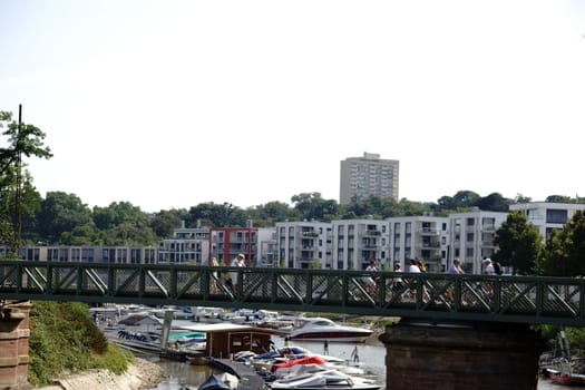 Mainz,Germany – August 22,2015: Pedestrians and cyclists cross a bridge on the Victor-Hugo-Ufer with an inland port and motorboats on August 22,2015 in Mainz.