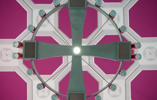 A large round ceiling chandelier with halogen spotlights on a distinctively panelled ceiling.