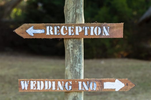 Direction signs for wedding inquiries and reception outside rural countryside wood pole materials.