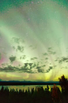 The Northern Lights emerge through the clouds in remote Alaska