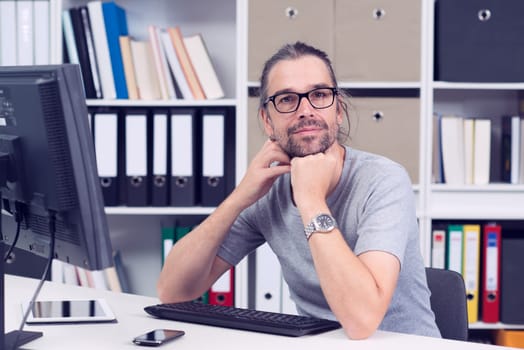 creative man is working in his office and looking in to the camera