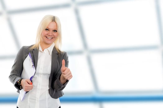 smiling blond young business woman with a clipboard and thumb up