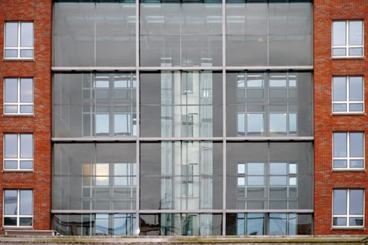 A modern house made of a glass facade and brick.