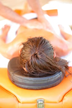 Massage therapist working with suntanned beautiful woman at beach resort