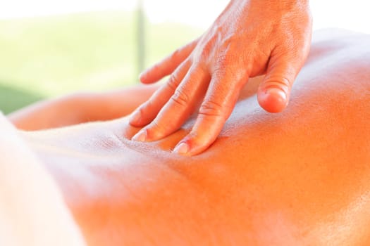 Massage therapist working with suntanned beautiful woman at beach resort