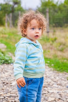 1 year old baby boy walking through the countryside.