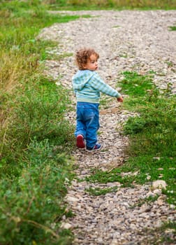 1 year old baby boy walking through the countryside.