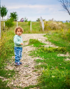 1 year old baby boy walking through the countryside.