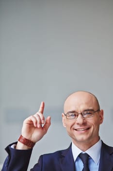 Successful businessman in eyeglasses pointing upwards