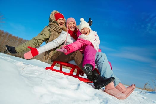 Ecstatic family on sledge having fun in winter