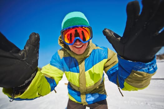 Snowboarder in sportswear and goggles standing in front of camera