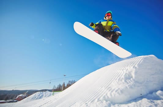 Active young man on snowboard hanging over snowdrift