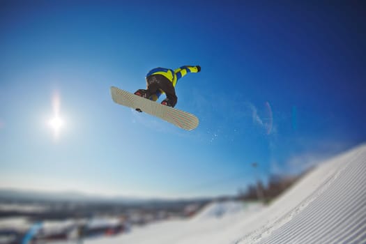 Sportsman snowboarding in winter against blue sky