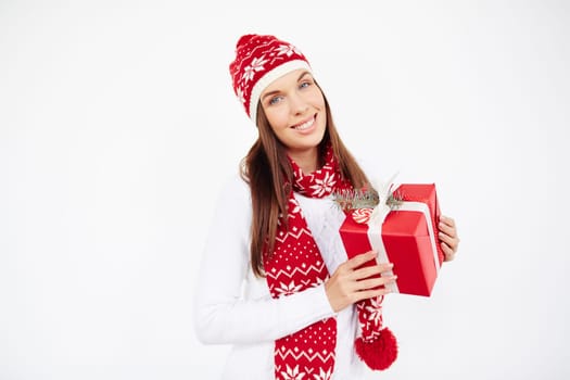 Happy girl in cap, sweater and scarf holding present