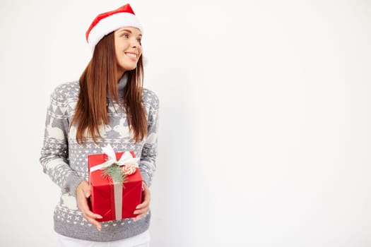Happy woman in sweater and Santa cap holding Christmas gift