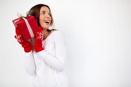 Surprised girl with Christmas gift by her ear