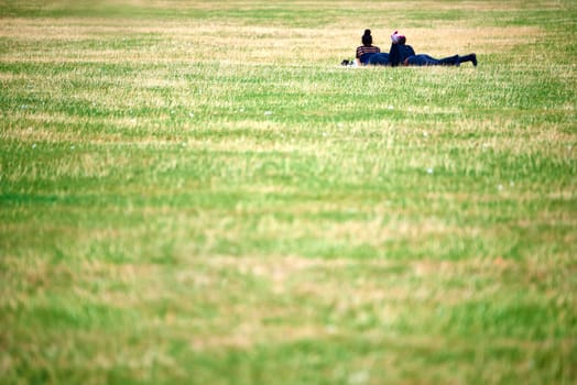 Two unrecognisable women lying on the green grass in the park