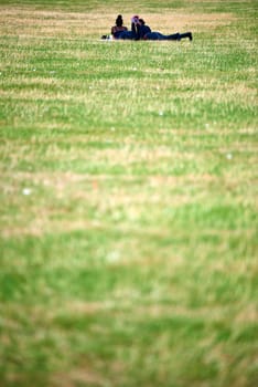 Two unrecognisable women lying on the green grass in the park