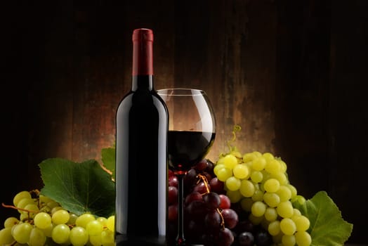 Composition with glass, bottle of red wine and fresh grapes