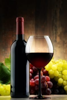 Composition with glass, bottle of red wine and fresh grapes