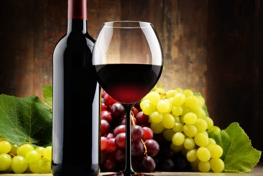 Composition with glass, bottle of red wine and fresh grapes